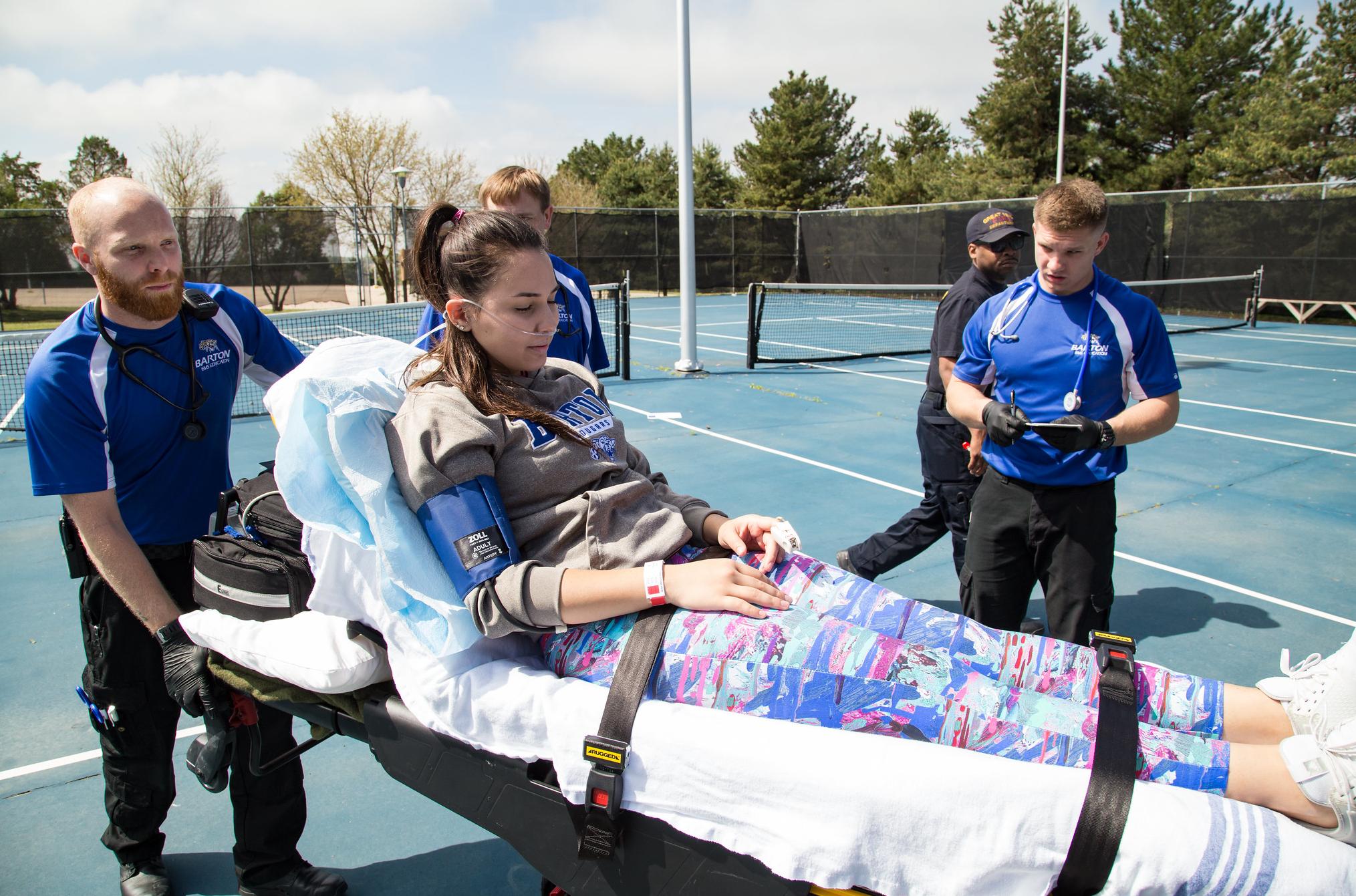 emt students push a patient on a stretcher