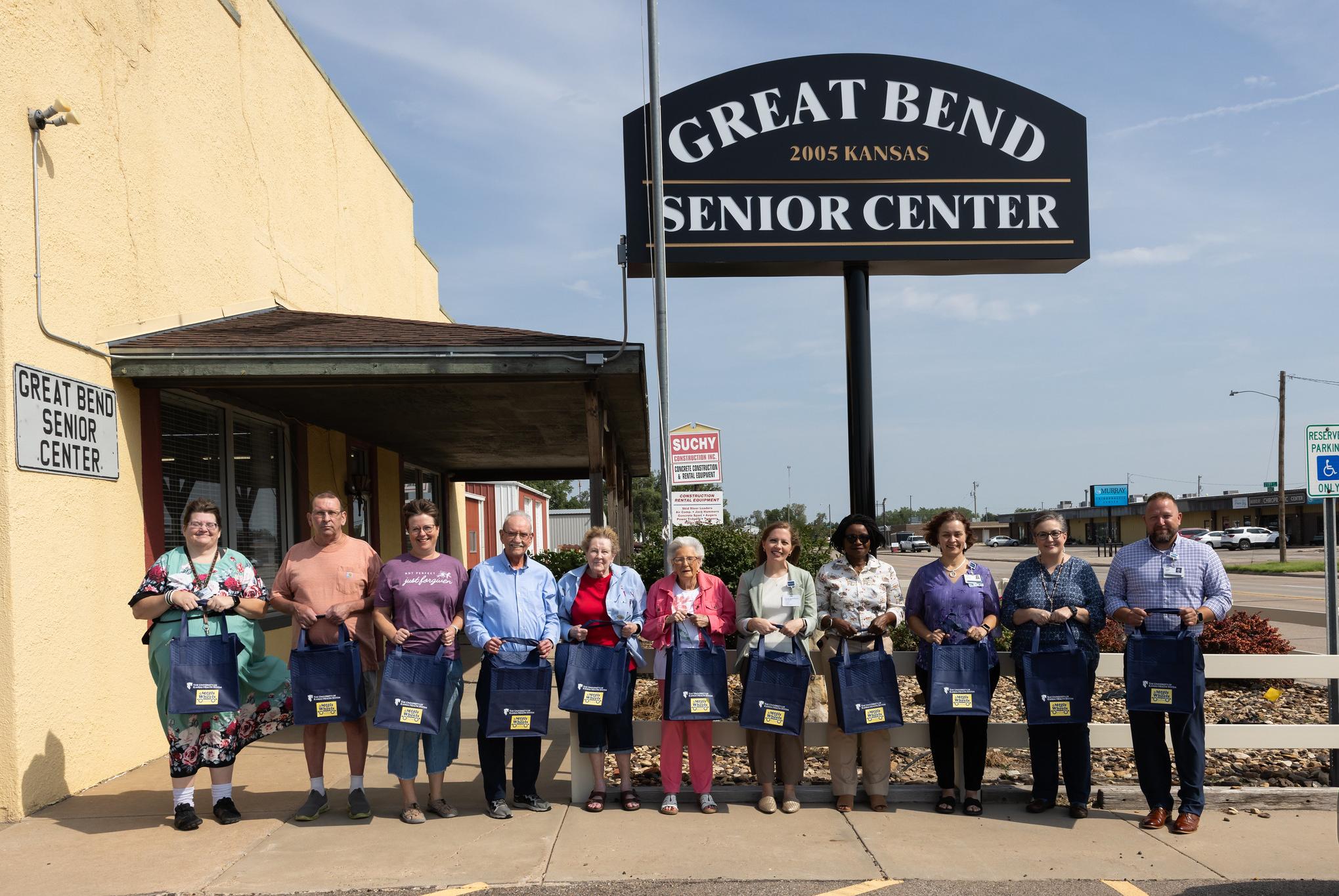 people standing in a line holding insulated food bags at a senior citizen center